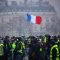 Demonstrators gather near the Arc de Triomphe as a French flag floats during a protest of Yellow vests (Gilets jaunes) against rising oil prices and living costs, on December 1, 2018 in Paris. - Anti-government protesters torched dozens of cars and set fire to storefronts during daylong clashes with riot police across central Paris on December 1, as thousands took part in fresh "yellow vest" protests against high fuel taxes. (Photo by - / AFP)